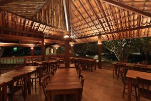 odkrytą restaurację z drewnianymi stołami i krzesłami w obiekcie Pousada Sitio da Prainha w mieście Praia dos Carneiros