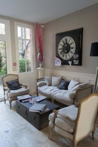 a living room with couches and a clock on the wall at Logis Hotel Restaurant Le Cheval Blanc in Bléré