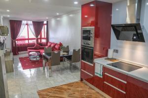コラレホにあるAppartamento Corralejoのキッチン(赤いキャビネット付)、リビングルーム(テーブル付)