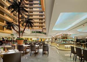 香港的住宿－香港帝苑酒店，一间设有桌椅的餐厅,并种植了棕榈树