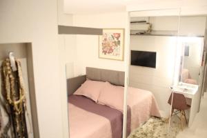 a small bedroom with a bed and a mirror at Apartamento Emaús in Parnamirim