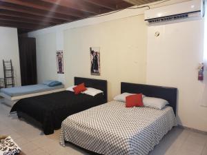 a bedroom with two beds and a bench in it at Jardin del Mar Guesthouse in Hatillo