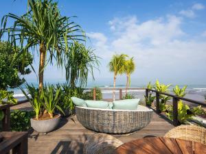 a patio with a table and chairs and the ocean at Noku Beach House by Elite Havens in Seminyak