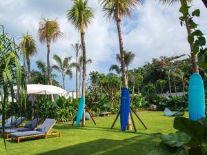 a group of chairs and palm trees in a yard at Noku Beach House by Elite Havens in Seminyak