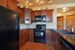 een keuken met een zwarte koelkast en houten kasten bij Bighorn Mountain 19B Condo in Estes Park