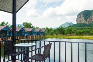 Baannai Lake View Resort في شاطيء آونانغ: بلكونه مع طاوله وكراسي مطله على النهر