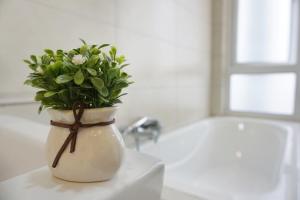 a white vase with a plant in it on a sink at PM Octagon Ipoh Suites & Apartment 2 in Ipoh +33 photos
