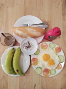 une table avec deux assiettes de denrées alimentaires avec des œufs et des bananes dans l'établissement Thanh An 2 Guesthouse, à Hue