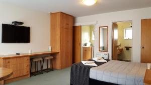 Aalton Motel في كرايستشيرش: غرفة نوم بسرير ومكتب وتلفزيون