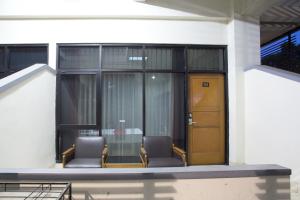 two chairs sitting in front of a building with a door at RedDoorz @ Surapati in Bandung