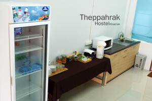 a small kitchen with a refrigerator and a table at Theppahrak Hostel Khaolak in Khao Lak