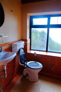 a bathroom with a toilet and a sink and a window at Hotel At The End Of The Universe in Nagarkot