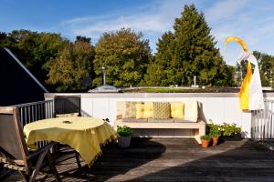 a patio with a couch and a table on a deck at Rooftop 52, City-Apartment in Assen