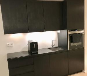 una cucina con armadi neri e lavandino di City View Apartment, free parking a Pärnu