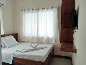 a bedroom with a bed with a heart towel on it at Argamosa Bayside Inn in Coron