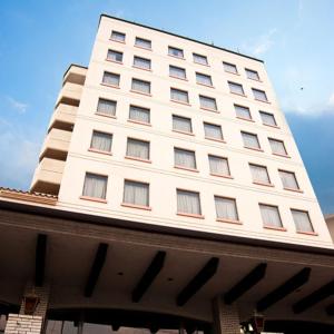 岛原市Shimabara Station Hotel的一座高大的白色建筑,有许多窗户