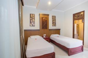 a room with two beds in a room with a window at Sinar Bali Hotel in Legian