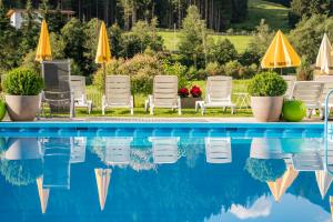 a swimming pool with lawn chairs and umbrellas at Bergsporthotel Antonie in Gries im Sellrain