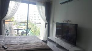 a bedroom with a flat screen tv and a large window at 馬爾代夫渡假式公寓酒店 in Pattaya South