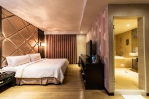 1 dormitorio con cama, TV y baño en The Riverside Hotel Fashion, en Kaohsiung