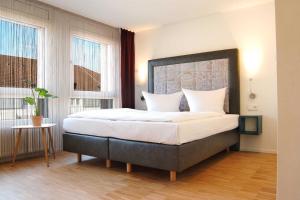 a bedroom with a large bed and two windows at SEEGER Living Premium Downtown in Karlsruhe