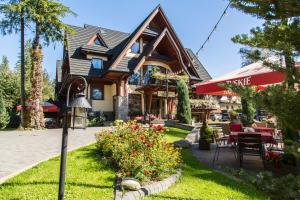 a house with a patio and flowers in front of it at Hotel Willa Pod Skocznią in Zakopane