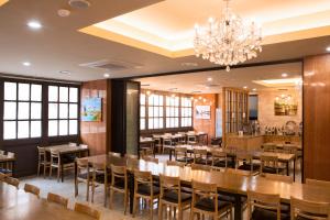 a restaurant with wooden tables and chairs and a chandelier at Hotel Sopra Incheon Cheongna in Incheon