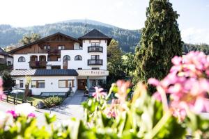 duży biały budynek z różowymi kwiatami na pierwszym planie w obiekcie Ferienhotel Bergland w mieście Arzl im Pitztal