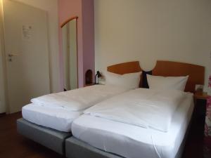 Garni Hotel Kaiserdom في بامبرغ: سريرين في غرفة ذات أغطية ووسائد بيضاء