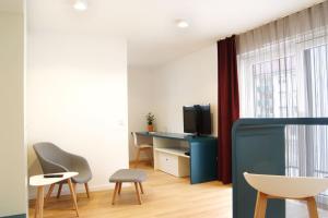 a living room with a tv and a table and chairs at SEEGER Living Premium West in Karlsruhe