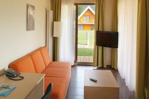 un salon avec un canapé orange et une télévision dans l'établissement Terme Topolsica Apartments, à Topolšica