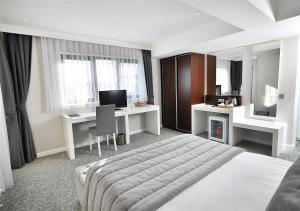 a bedroom with a bed and a desk and a television at Güvenay Business Hotel in Ankara