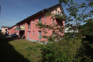 ein rosafarbenes Gebäude mit einem Balkon an der Seite in der Unterkunft Haus Clara Wohnung 05 in Ostseebad Koserow