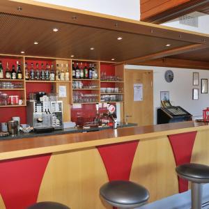 a bar in a restaurant with two red stools at Hotel Restaurant Emshorn in Oberems