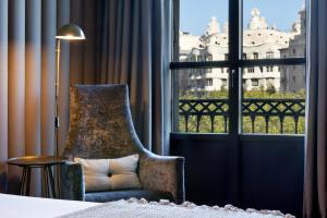 um quarto com uma cadeira e uma grande janela em Condes de Barcelona em Barcelona