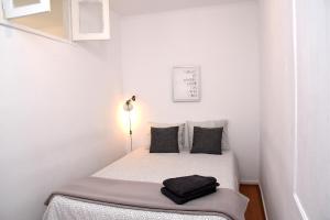 リスボンにあるTravessa do Jardim Apartmentの白い小さな客室で、ベッド1台(黒い枕付)が備わります。