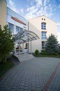 a white building with a metal canopy in front of it at Hotel Atrium in Târgu Secuiesc