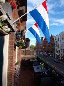 a flag flying on a balcony with tables and a street at Hotel Clemens in Amsterdam