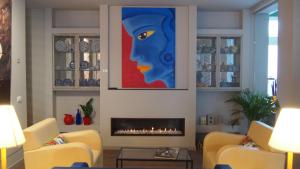 a living room with a fireplace and a painting of a woman at Hotel Lucerna in Castiglione della Pescaia