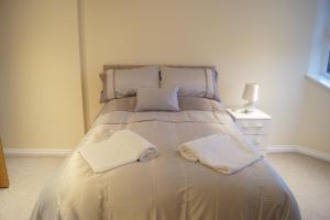 a bed with two white towels on top of it at Modern, Cosy Apartment In Bearsden with Private Parking in Glasgow