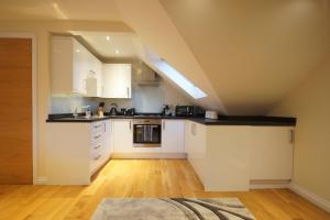 Modern, Cosy Apartment In Bearsden with Private Parking في غلاسكو: مطبخ في العلية مع دواليب بيضاء