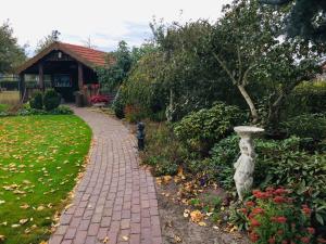 een stenen loopbrug met een standbeeld in een tuin bij Bed & Breakfast 'Het Oude Nest' in Kessel