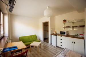 a living room with a green couch and a kitchen at Apartments Pod Kotlom in Vysoké Tatry
