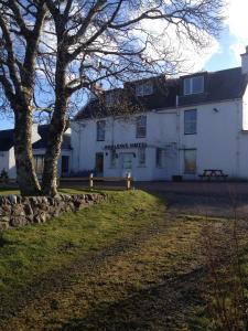 a white building with a tree in front of it at Poolewe Hotel in Poolewe