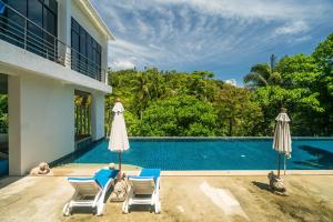a villa with a swimming pool and two chairs and umbrellas at The Palm at Veloche Group by Lofty in Karon Beach