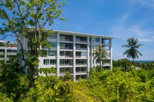a white building with trees in front of it at The Palm at Veloche Group by Lofty in Karon Beach