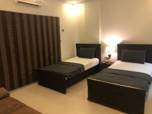 een kamer met 2 bedden in een kamer bij Sunset Suites in Karachi