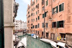 ein Kanal zwischen zwei Gebäuden mit Booten im Wasser in der Unterkunft Cannaregio Canal View - Marco Polo in Venedig