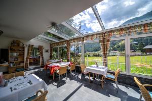 a conservatory with tables and chairs and a large window at Hotel Schwarzbachhof in Lutago