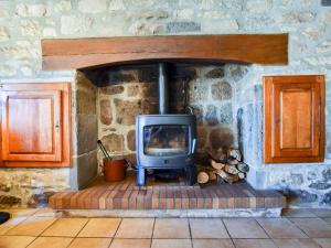 chimenea de piedra con estufa en la habitación en Comfy holiday home with private garden, en Neuvéglise